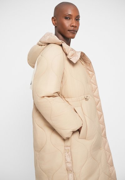 Példával párnázott bézs kabát, texturált, steppelt dizájnnal, kapucnival, elülső zsebekkel és selyem részletekkel a cipzáron és a szegélynél.