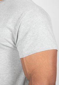 Grijze t-shirt met korte mouwen, gemaakt van zachte stof, toont een close-up van de mouw en schouder met een gladde textuur en nette stiksels.