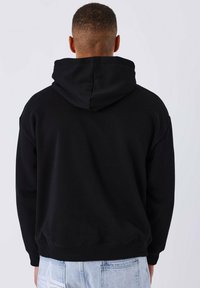 Zwarte hoodie met een relaxte fit en geribde manchetten, gezien van achteren. De stof is zacht met een gladde textuur.
