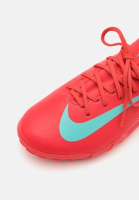 Jasne červené športové topánky s textúrovaným povrchom, s tyrkysovým logom Nike, okrúhlymi šnúrkami a nízkym strihom.