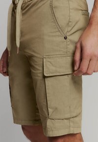 Katoenen cargoshorts in olijfgroen met een trekkoord in de taille, zijzakken en een klepzak op de dij, met gestikte details.