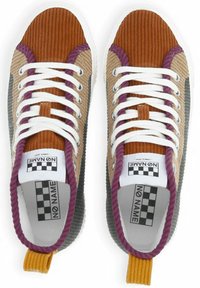 Sneakers with a mixed corduroy upper in brown, beige, and gray, featuring white laces, purple accents, and a yellow pull tab at the heel.