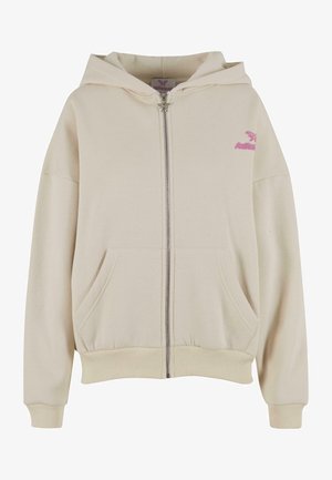 Krämfärgad dragkedja hoodie med en stor ficka fram och ribbade muddarna. Har en rosa logotyp på vänster bröst och en rymlig huva. Mjuk textur.