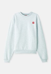 Sudadera azul clara en una tela suave y texturizada. Presenta un cuello redondo acanalado y puños, con un pequeño parche de logo rojo en el pecho.