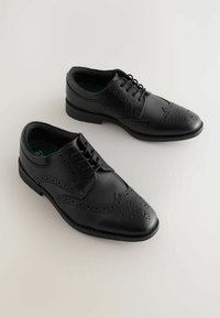 Chaussures habillées en cuir noir avec des détails brogue, présentant un laçage à l'avant, un bout rond et une semelle intérieure texturée. Design classique avec une surface lisse.