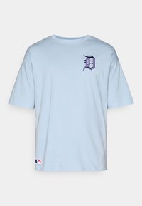 Šviesiai mėlynas medvilninis marškinėlis trumpomis rankovėmis. Geroje krūtinės vietoje puikuojasi violetinė siuvinėta "D" logotipas ir MLB etiketė apatinėje dalyje.