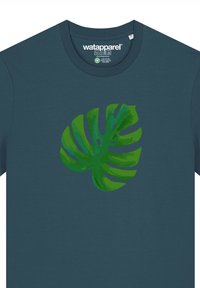 Teal katoenen t-shirt met een groene monstera bladgrafiek. Zachte textuur, crew neck, korte mouwen, met label zichtbaar aan de binnenkant van de halslijn.