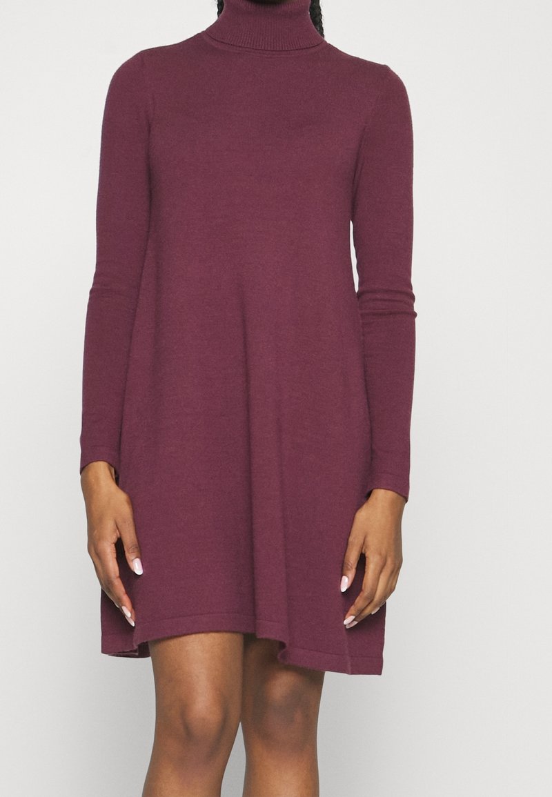 Robe à col roulé à manches longues en maille bordeaux foncé, avec une coupe ample et un ourlet au-dessus du genou. Texture douce, design minimaliste.