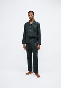 Pigiama da uomo in un motivo a quadri blu navy con accenti verdi. Il set include una camicia con bottoni e pantaloni abbinati in un tessuto morbido.