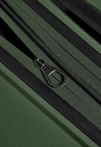 Borsa con cerniera in tessuto verde testurizzato, dotata di una cerniera nera e di un tirante, che mostra una superficie liscia e dettagli di colore a contrasto.