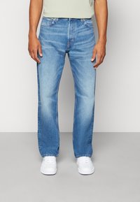 Jeans in denim azzurro chiaro con design a gamba dritta. Caratterizzati da leggeri sbiadimenti, stile classico a cinque tasche e dettagli di cucitura arancione.