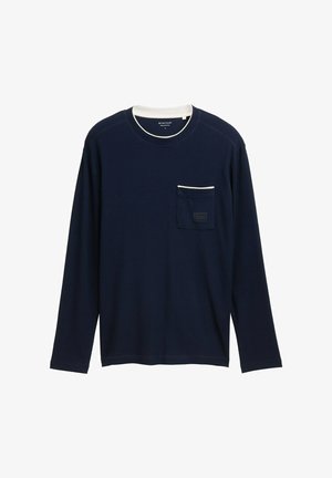 Maglietta a maniche lunghe blu navy realizzata in tessuto testurizzato, con una piccola tasca sul petto con bordi bianchi e etichetta. Collo rotondo e design semplice.
