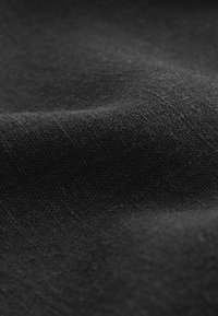 Tejido negro con una trama texturizada. El material parece suave y liso, con sutiles variaciones en el tono y la reflexión de la luz.