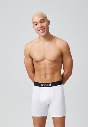 Weiße Baumwoll-Boxershorts mit einem schwarzen elastischen Bund, auf dem das Logo "SNOCKS" zu sehen ist. Sie haben eine glatte Textur und eine körpernahe Passform.