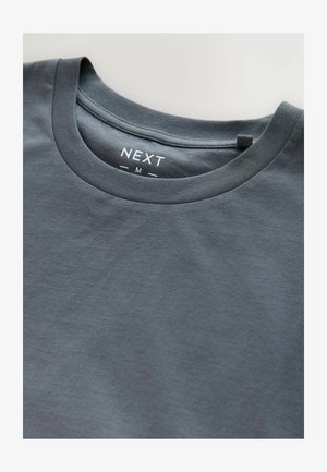 Tricou din bumbac gri, cu guler rotund, mâneci scurte și un mic etichetă pe guler cu marca "NEXT" și mărimea "M."