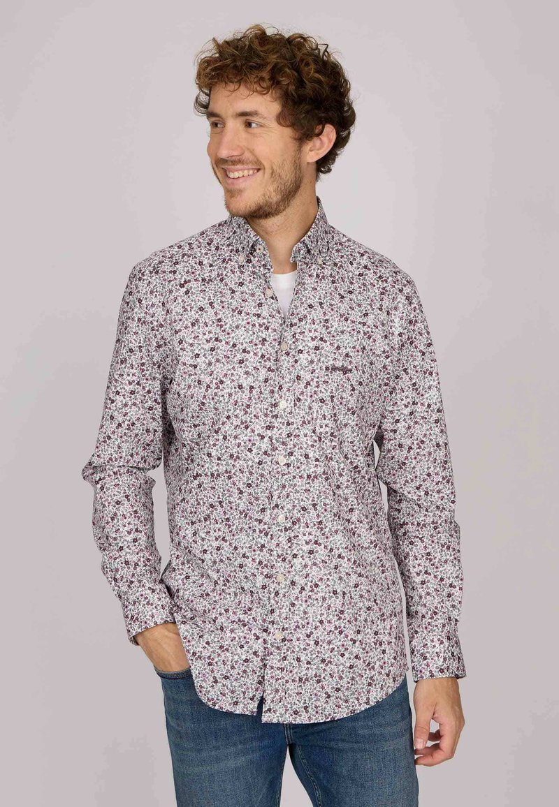 Chemise à manches longues boutonnée avec une base blanche et de petits motifs floraux rouges et verts. Elle présente un col classique et une poche poitrine.