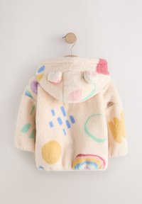 Veste pelucheuse de couleur crème avec une capuche, ornée de motifs géométriques colorés en rose, bleu, jaune et vert. Texture douce, accents en pompons.