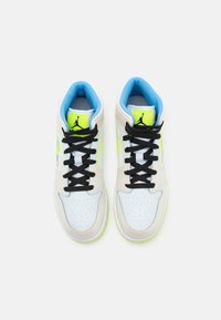 Bílé a béžové tenisky s černými šňůrkami, modrou podšívkou a neonově zelenými akcenty. Kulatá špička, perforovaný svršek a texturovaná podešev.