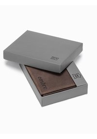 Bruin leren portemonnee met tan stiksels, gelabeled "ombre," binnenin een grijze RFID-veilige doos. De doos heeft een minimalistisch ontwerp en logo.