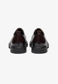 Brown leather shoes with a smooth finish, featuring a rounded toe, thick black rubber sole, and elastic heel pull tabs.