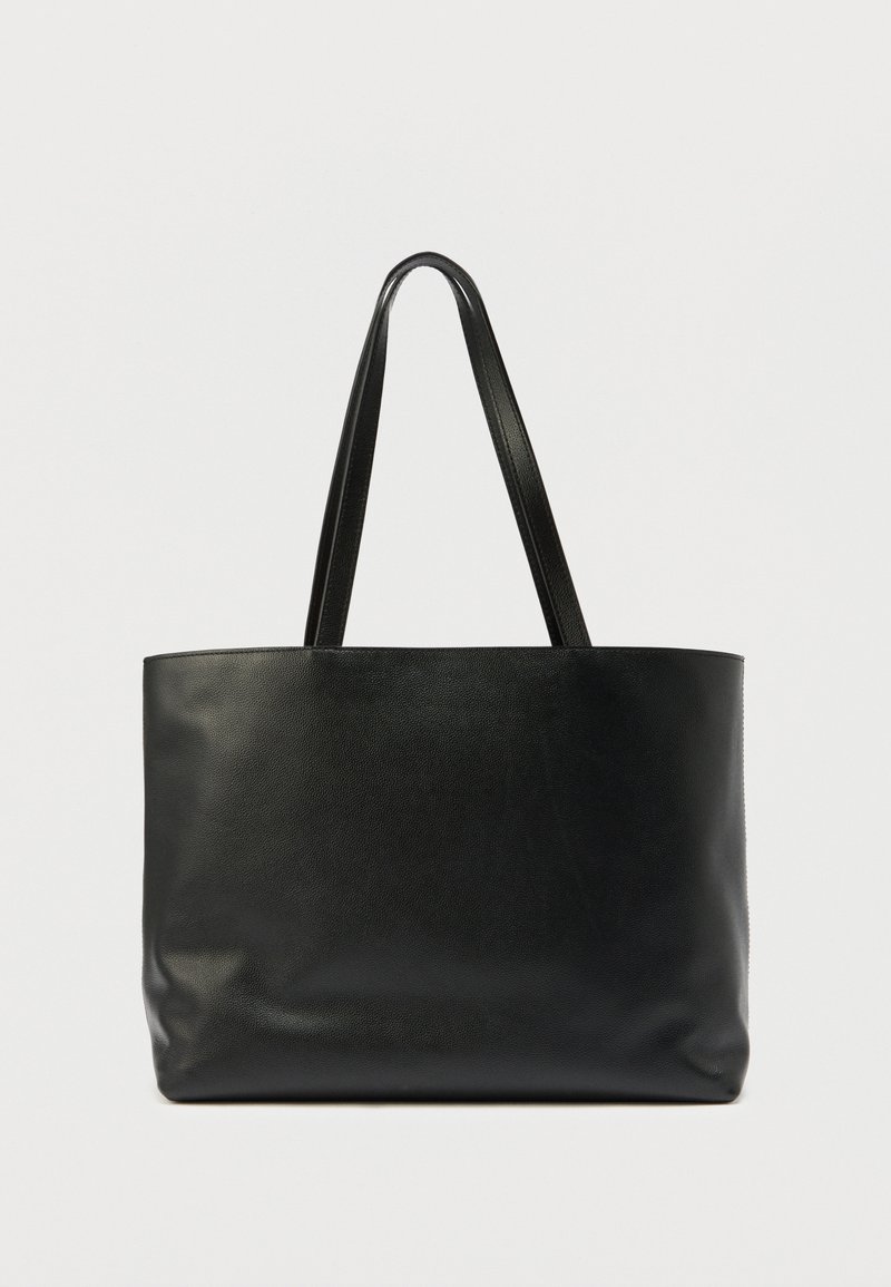 Černá kožená taška přes rameno s dvěma dlouhými plochými úchyty. Hladká textura a jednoduchý design, otevřený vrch bez dalších kovových doplňků.