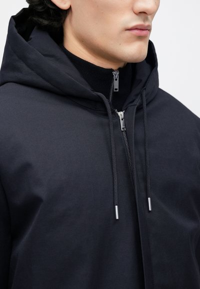 Must kapuutsiga jakk, millel on sile kangapind, eesmine tõmblukk ja metallotsadega paelad. Kapuuts on külje pealt nähtav.