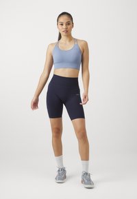 Lys blå atletisk crop top med tynne stropper, kombinert med høyt liv mørkeblå sykkelshorts med sidelomme og glatt tekstur.