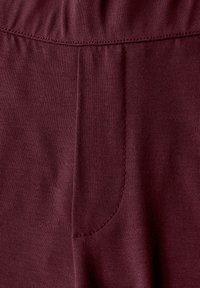 Bordeaux leggings med en slät och elastisk tygkvalitet, ett elastiskt midjeband och en enda sidoficka med diskreta sömdetaljer.