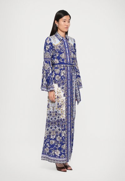 Robe longue bleue à motifs floraux avec un col, des manches cloche et une ceinture assortie. Présente des motifs dorés et blancs complexes.