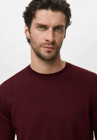 Burgundy knit sweater with a round neckline, smooth texture, and fitted design. No visible logos or patterns are present.