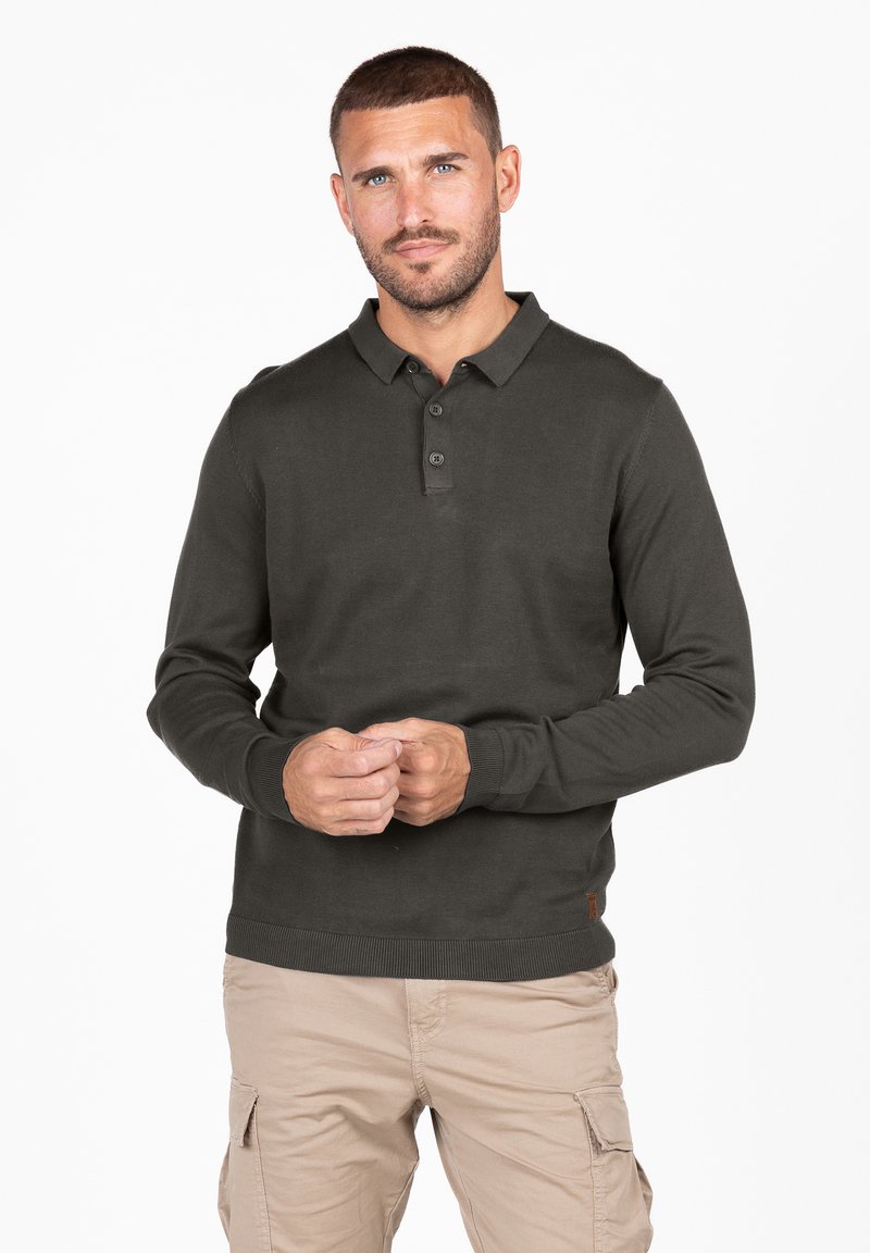 Polo shirt verde scuro a maniche lunghe con colletto, listino a tre bottoni e polsini a costine. Indossato con pantaloni cargo color khaki.