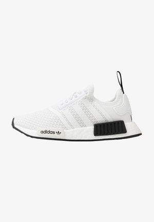 Baskets blanches Adidas NMD avec tige en mesh, trois bandes, languette de talon noire et accents noirs sur la semelle intermédiaire sur fond blanc.