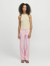 Beige ribbet tanktop med blomsterdesign, parret med lyserøde stribede wide-leg bukser. Modellen står på en ensfarvet baggrund iført brune sandaler.