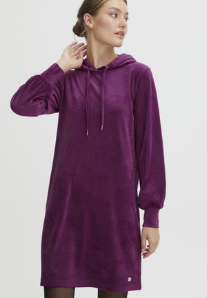 Lila huvtröja-kjol i mjukt tyg, med långa puffärmar, dragsko på huvan och en subtil logotyp nära fållen.