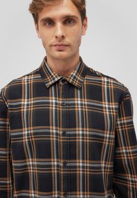 Schwarz-orange kariertes Hemd mit knöpfbarem Kragen, ausgestattet mit vertikalen und horizontalen Linien, aus weichem Stoff und in lässiger Passform.