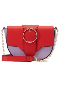 Červená a fialová kožená crossbody taška s kruhovým zlatým kroužkem, řetízkem, klopovým uzávěrem a zakřivenými dolními okraji.