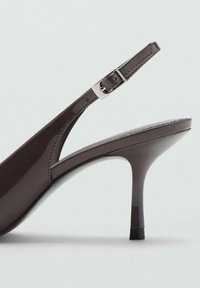 Rjav lakiran usnjen slingback čevelj z tanjšim stiletto peto, nastavljivim pasom s sponko in gladko površinsko teksturo. Minimalističen dizajn.