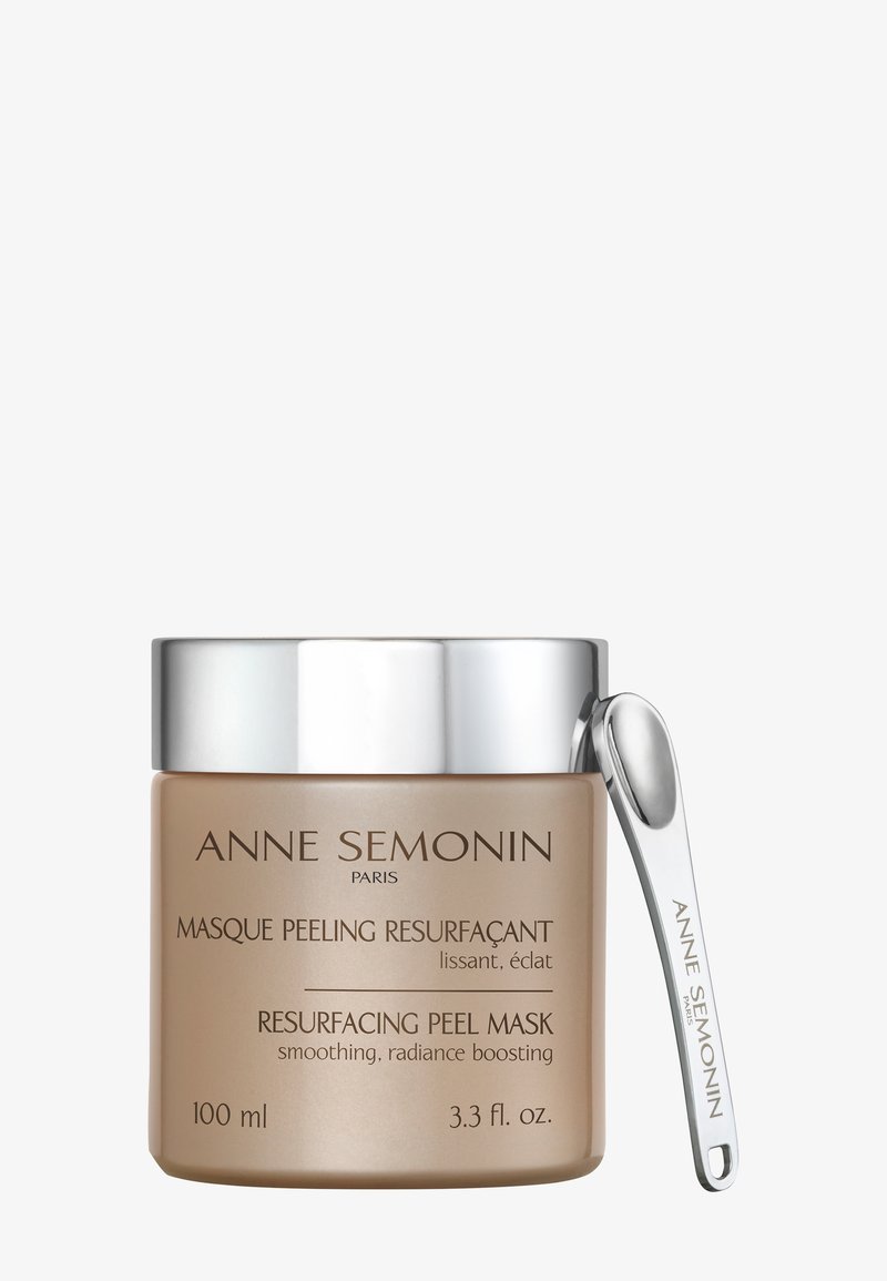 Un pot de 100 ml de masque peeling resurfaçant Anne Semonin avec couvercle argenté et petite spatule argentée fixée sur fond blanc.