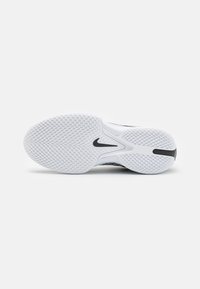 Hvit idrettssko såle med teksturert gummi for grep, med en svart Nike-logo og et strømlinjeformet design med avrundede kanter.