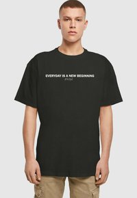 Sort bomulds t-shirt med korte ærmer, der har hvid tekst: "HVER DAG ER EN NY START #håb." Enkel, afslappet pasform.