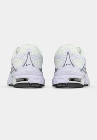 Ζευγάρι λευκών αθλητικών παπουτσιών Nike, με θέα από πίσω, που διαθέτουν επάνω μέρος από δι�χτυωτό υλικό, μαύρες σόλες και ορατή αερόσουπα στις φτέρνες.