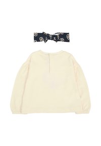 Top lungo a maniche con una tonalità chiara di crema, collo rotondo e polsini elasticizzati, abbinato a un cerchietto blu navy con un motivo floreale in crema e marrone.