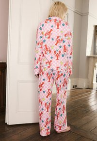 Rosa pyjamaset med mönster av hummer och stjärnor, tillverkat av mjukt tyg. Designen inkluderar långa ärmar och löst sittande byxor.