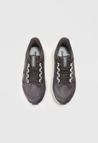 Baskets de sport gris foncé avec une tige en maille, accents blancs contrastants, six œillets et une pointe arrondie. Semelle légère et rembourrée.