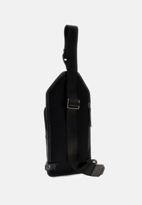 Borsa a tracolla nera con un lato in rete testurizzata e materiale liscio. Presenta una tracolla regolabile e un design minimalista con una tasca con zip.