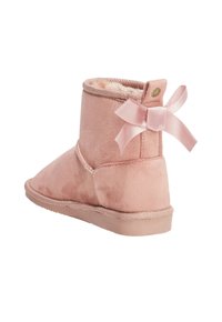Botín de ante rosa con un forro suave, suela plana y un lazo de satén en la parte trasera. Diseño de punta redonda con un detalle de costura.