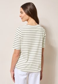 Gestreept T-shirt in crème met donkergroene horizontale strepen, korte mouwen, een ronde halslijn en een losse pasvorm. Katoenen materiaal, zachte textuur.