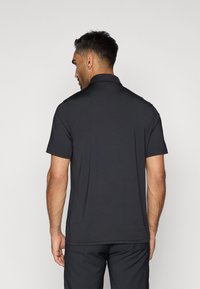 Polo shirt noir pour homme en tissu doux et léger ; doté de manches courtes, d'un col et d'un ourlet droit. Design épuré et simple.