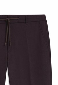 Mörk lila sweatpants med dragsko i midjan, sidfickor och ett mjukt, texturerat tyg. Enkel design utan ytterligare mönster.