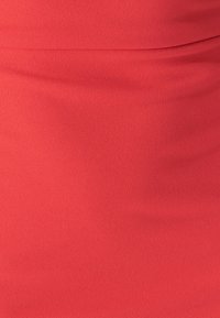 Rødt stof med en glat, tekstureret overflade. Materialet er blødt og falder flydende, med subtile folder for ekstra dybde.